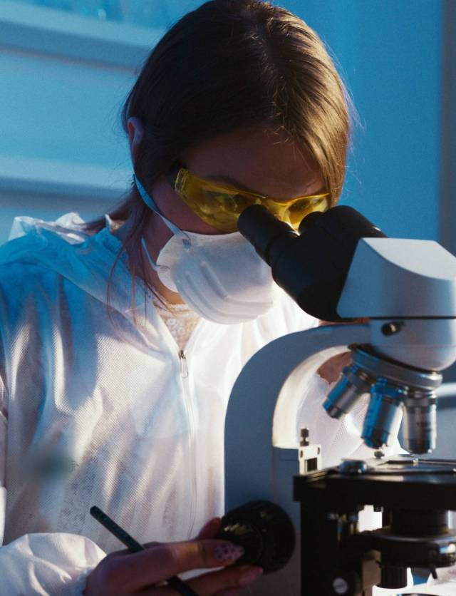 mujer mirando en un microscopio